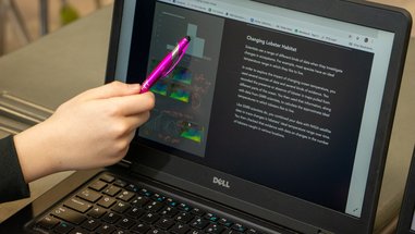 A student points a pink pen at an interactive display of Gulf of Maine data.