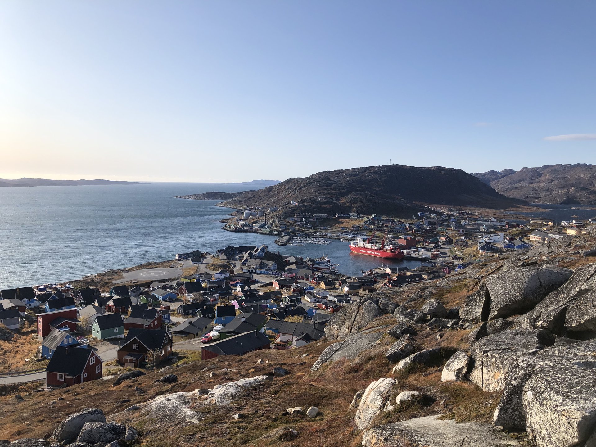 An aerial shot over Qaqortoq, a coastal town in Greenland on a sunny day.