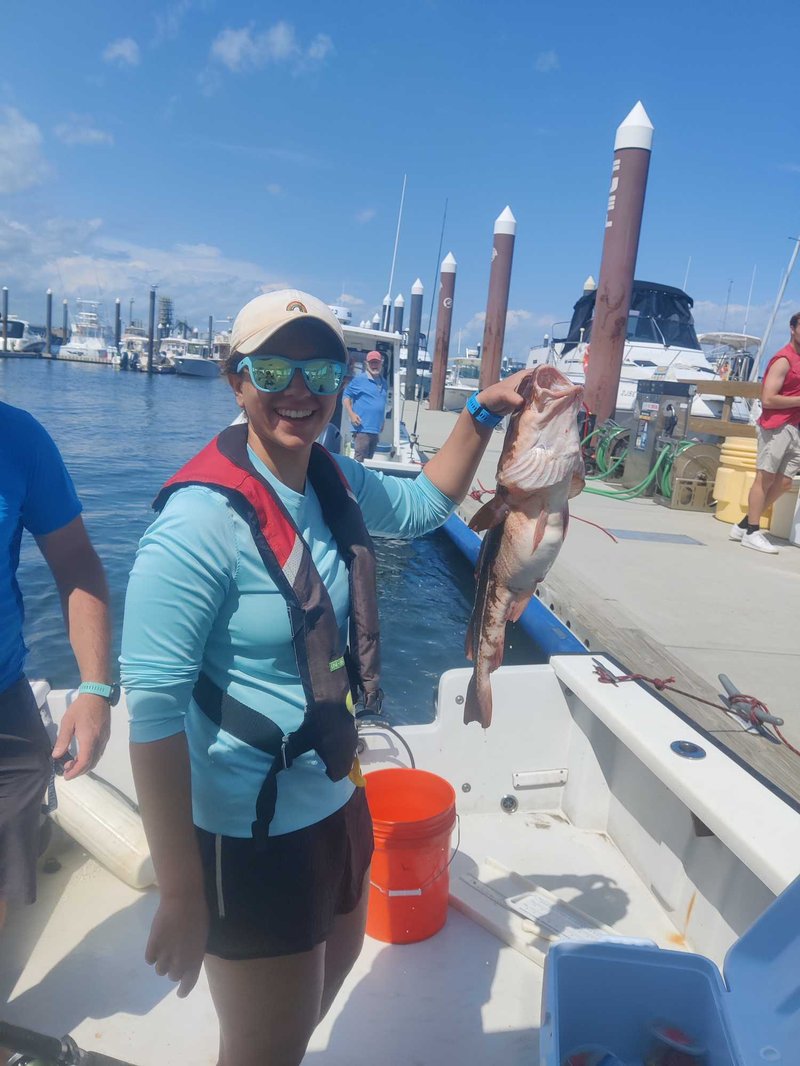 A young woman is smiling and holding a cod.