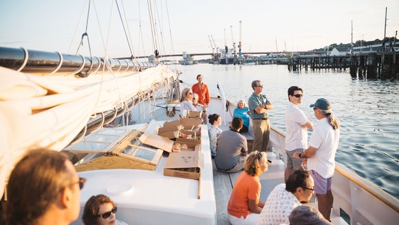 people aboard a sailboat at sunset on portland's waterfront
