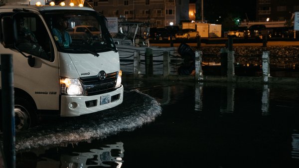 A truck drives through a flooded street at night.