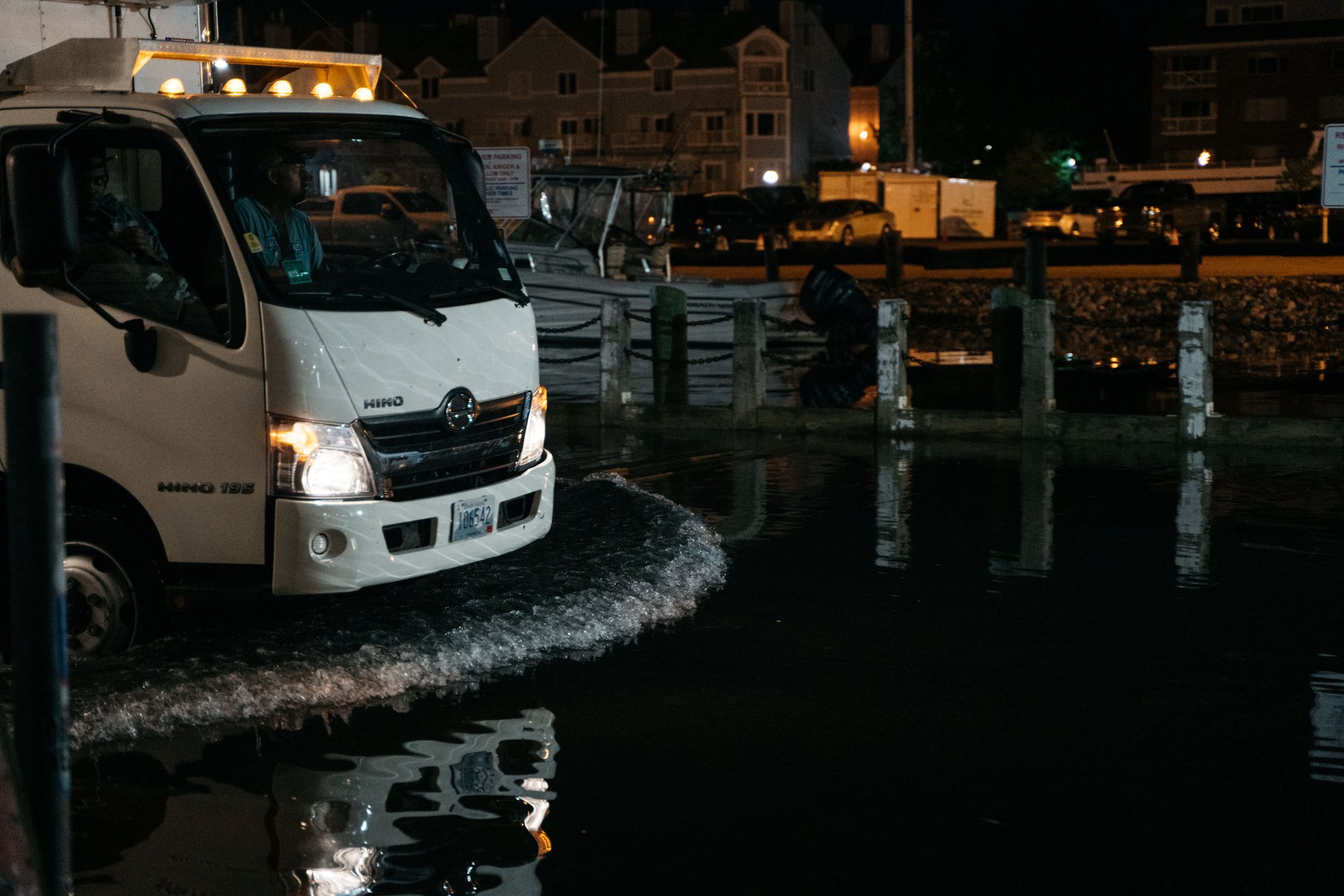 A truck drives through a flooded street at night.