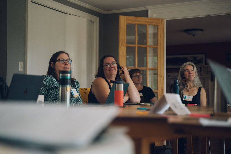 Educators gather around a table indoors.