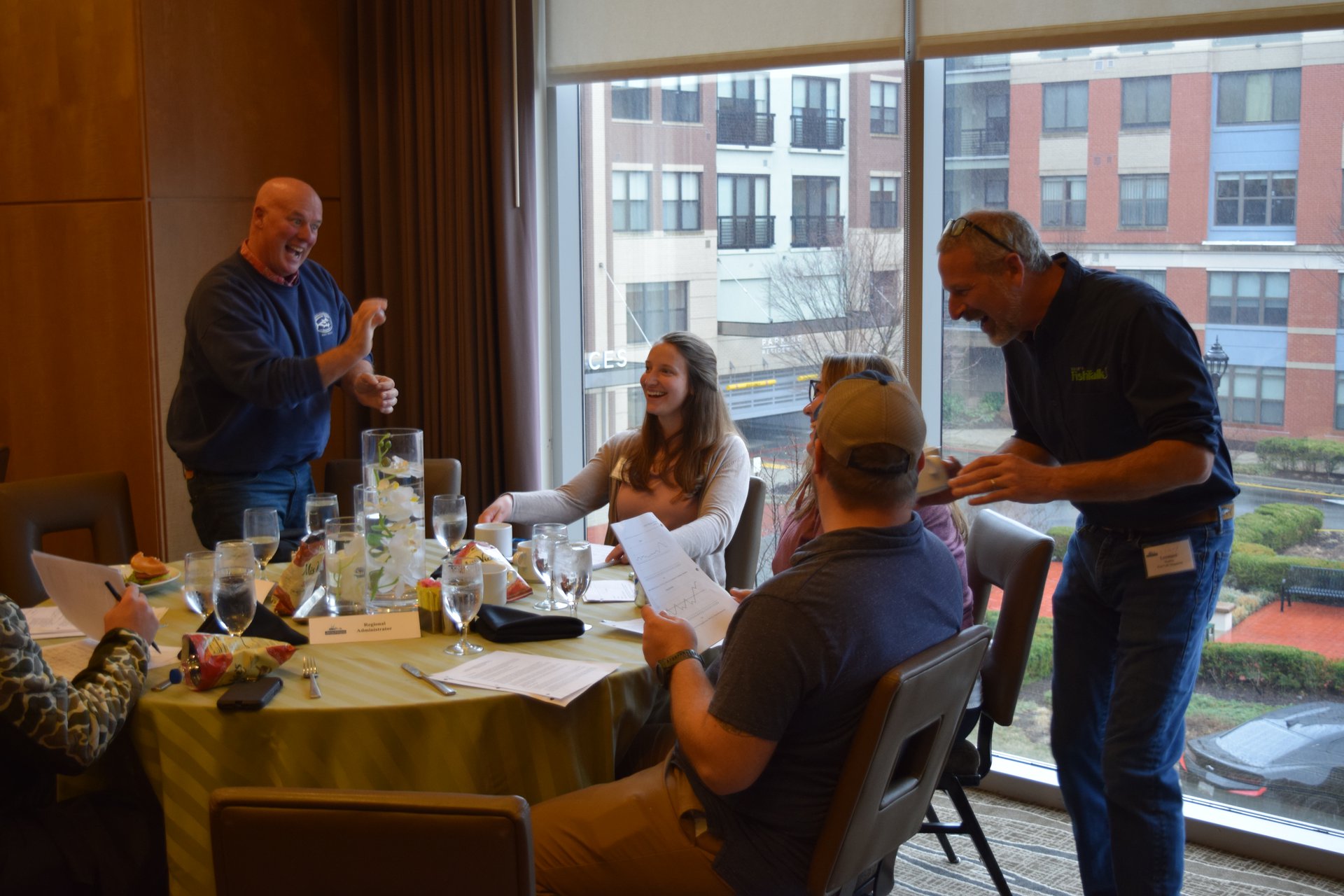 A group of people sit animatedly around a covered table.
