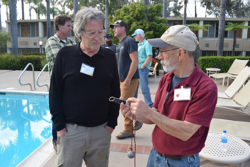 Two men are having a conversation near a pool.