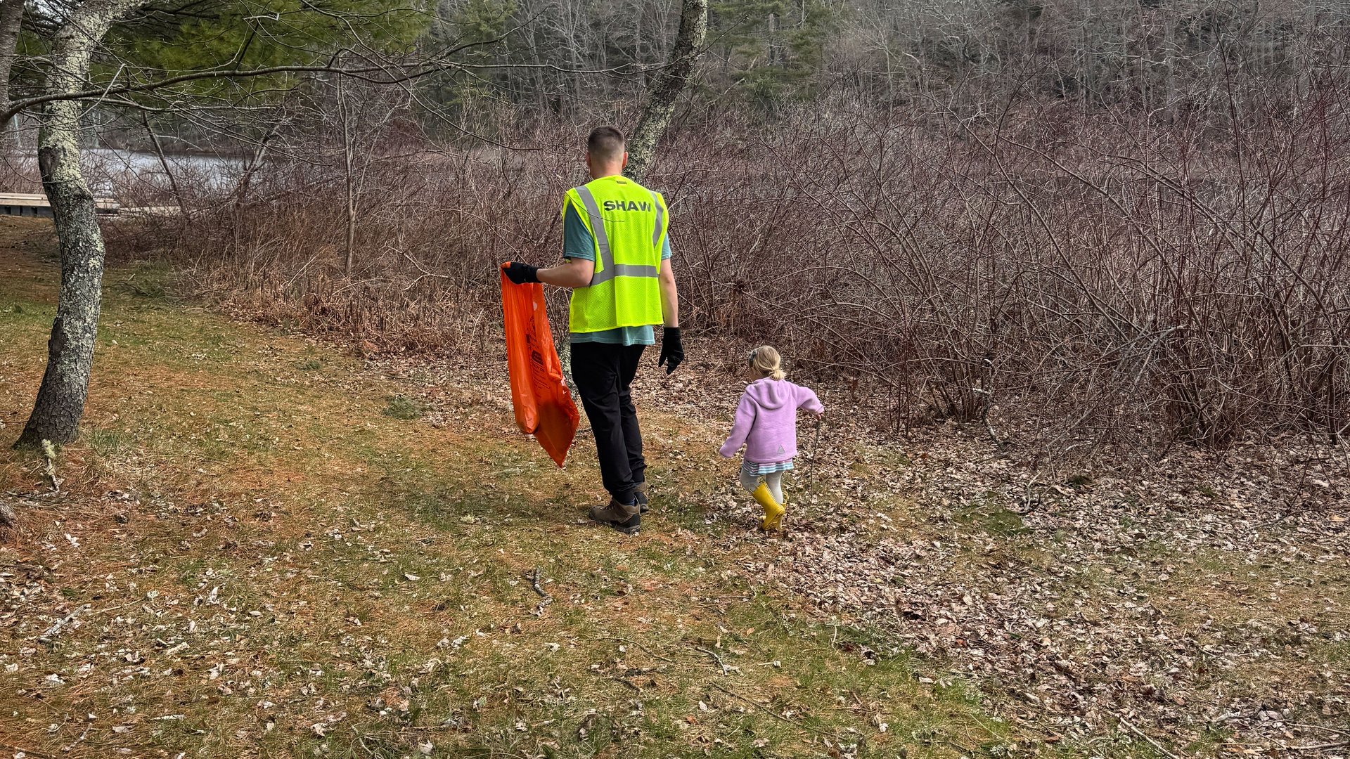 A dad and his daughter picking up trash.