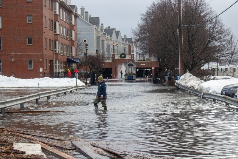 A man wades through the flooded road entrance to condominiums in Portland.