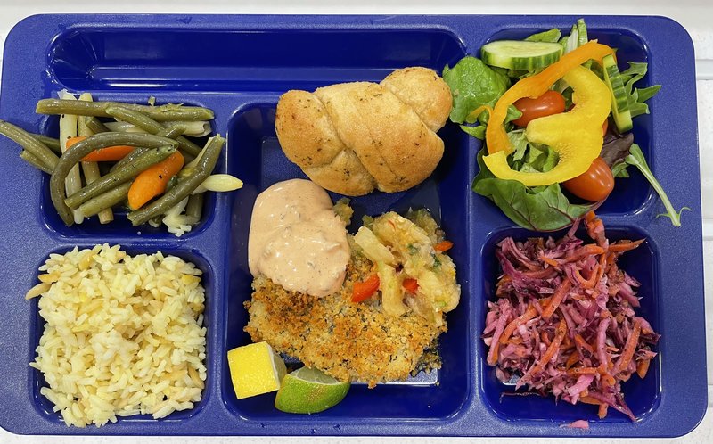 This is a photo of a school lunch on a blue tray with colorful veggies and seafood.