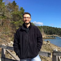 A portrait of a man smiling outside.