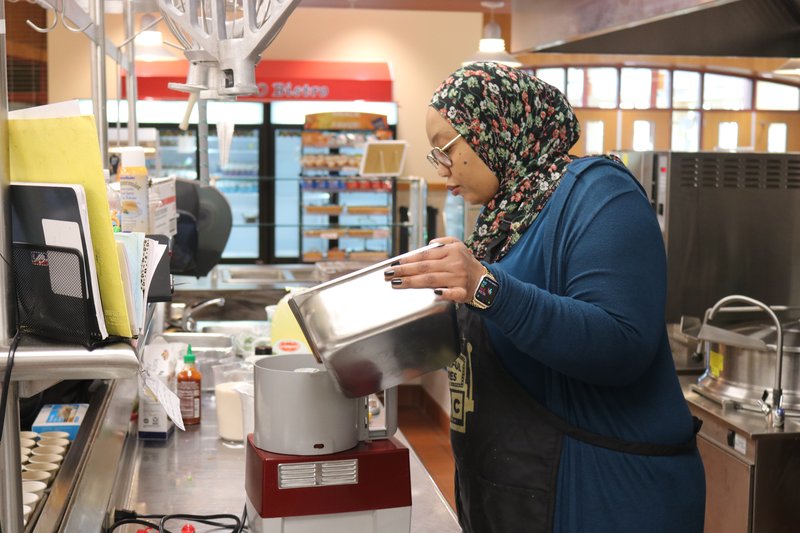 A woman pours food into a food processor.