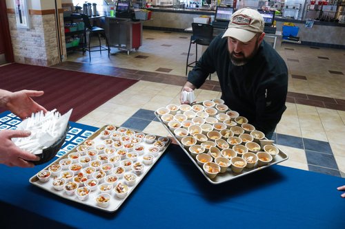 A chef places a tray of seafood onto a long table.