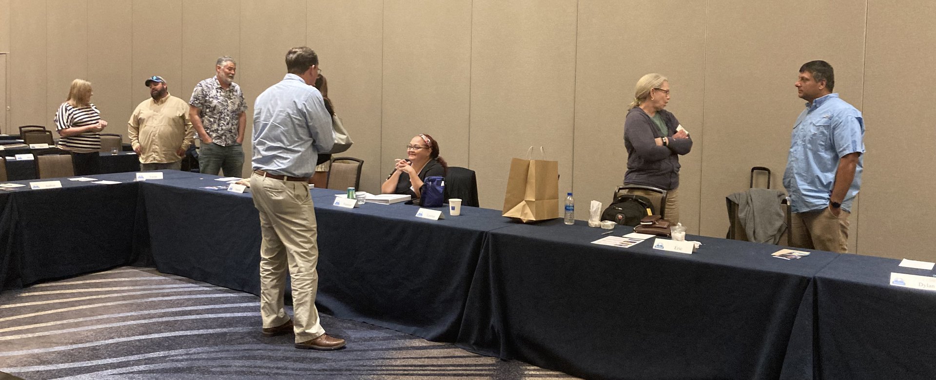 People gather around a long table, and are engaged in discussion.