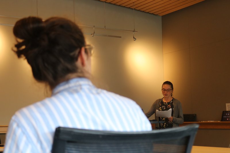 An intern presents their research while someone looks on.