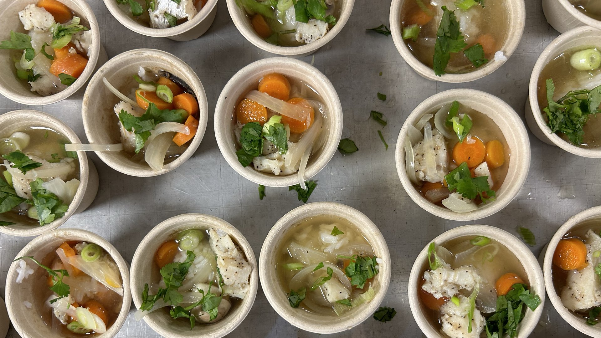 Seafood samples in cups waiting to be picked up on a table.