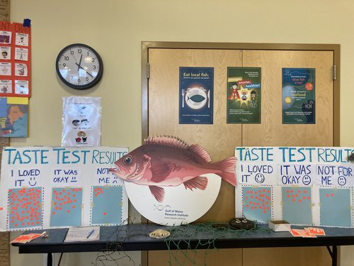 Posters with orange stickers flank a post of a big red fish.