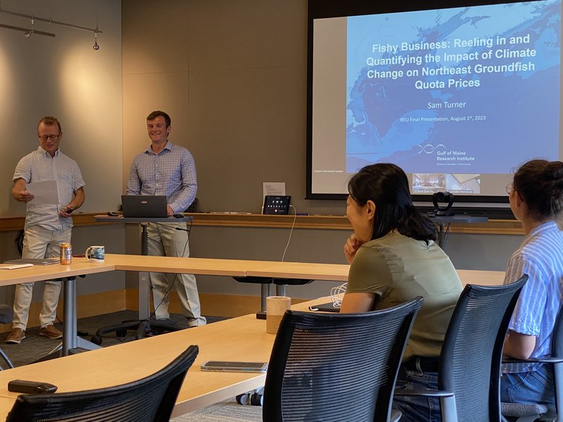 An intern stands at a podium ready to start a presentation to a group of people.