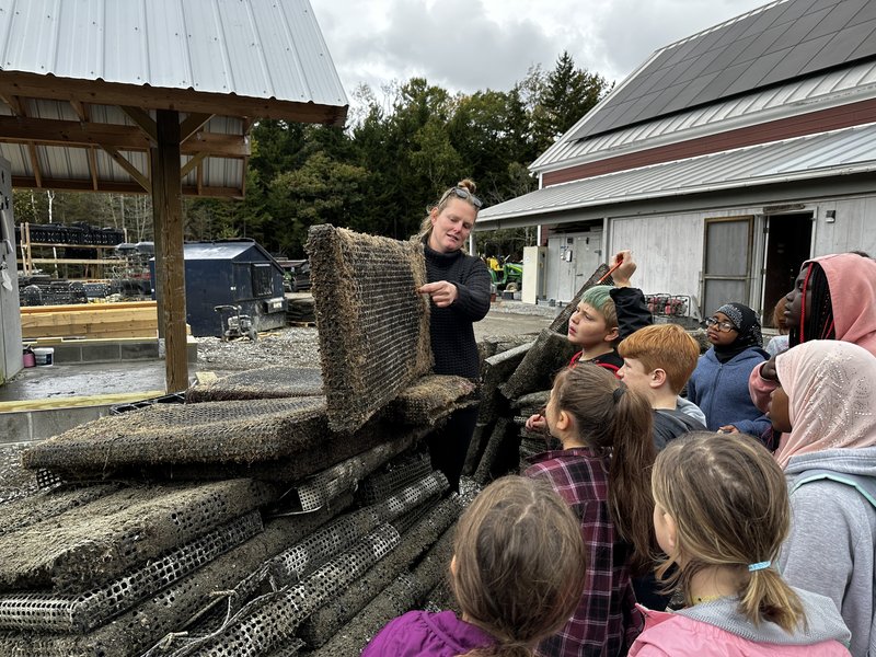 A group of students are being taught about aquaculture cages.
