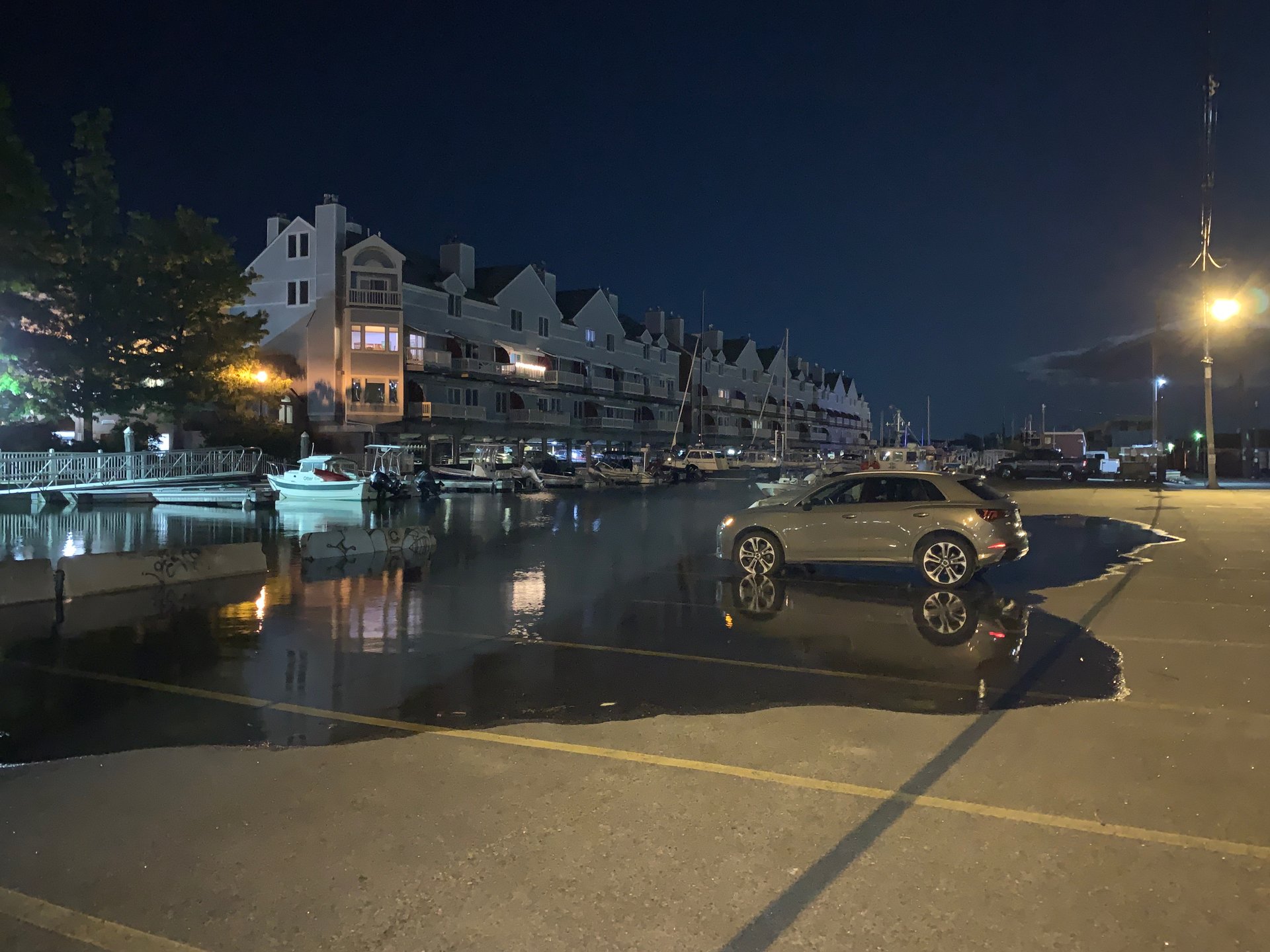 Water encroaches on a parked car as a high tide floods Portland on a moonlit night.