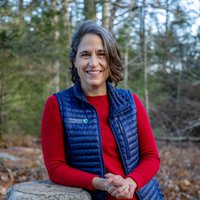 A portrait of a woman smiling in the woods.