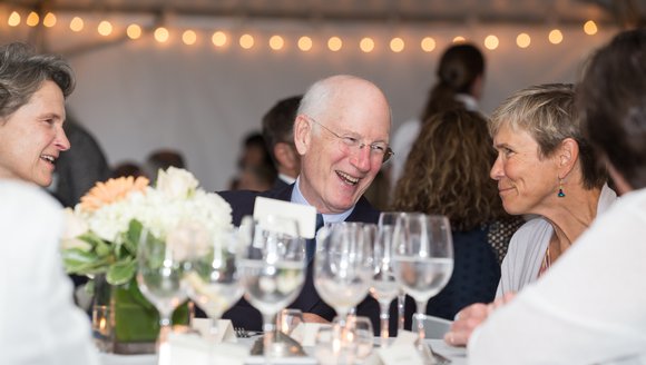 Cheery dinner guests at a table with wine glasses in front
