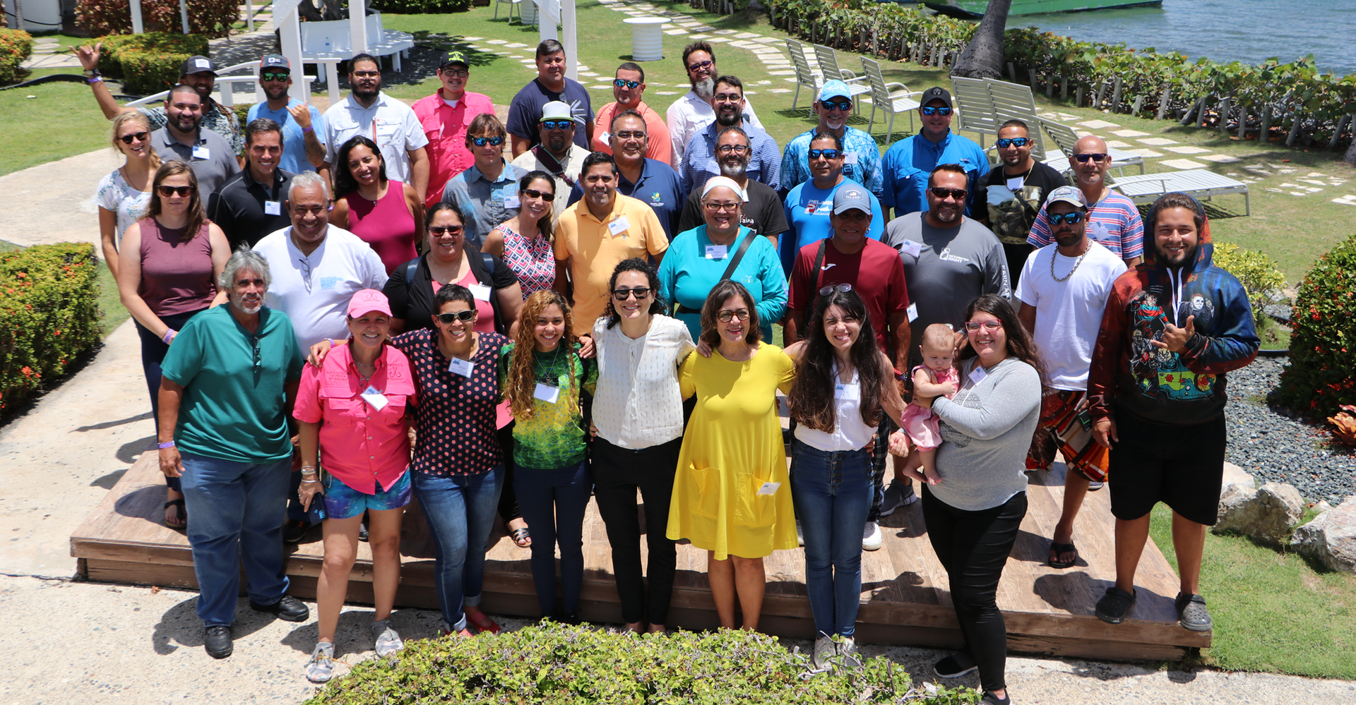 A group of men and women pose for a staged photo outside.