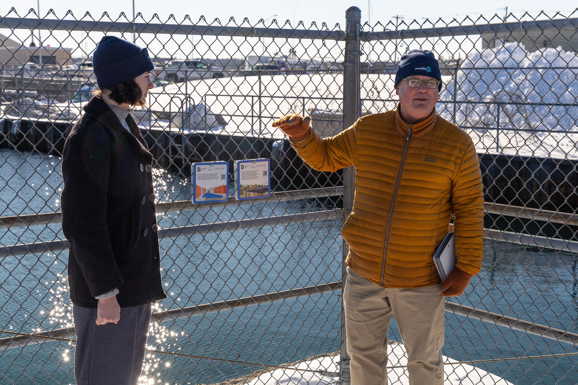 Troy Moon speaks about the climate impact signs on a fence while discussing sea level rise during the resolution event.