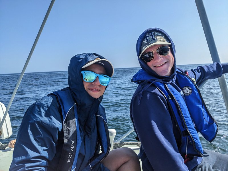 Two REU interns smile at the camera on a boat.