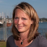 A portrait of a woman smiling, outside.