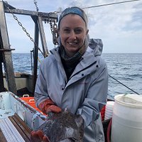 This is a portrait of a woman smiling, holding a fish.
