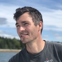 A portrait of a man in a gray shirt.