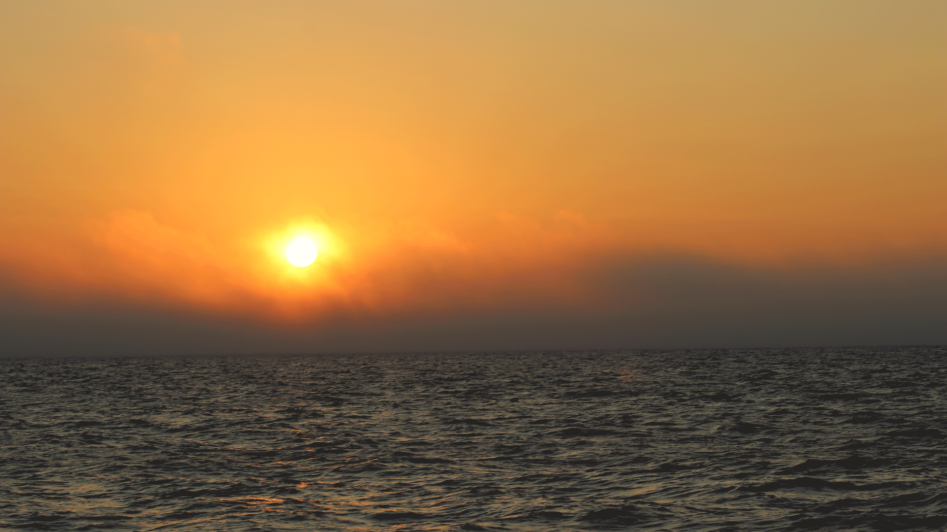 Fog clears on the ocean in the morning as the sun rises.