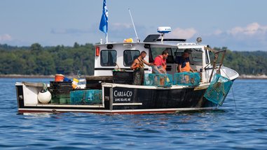 Lobsterman hauling and putting bait in lobster traps on a lobster boat