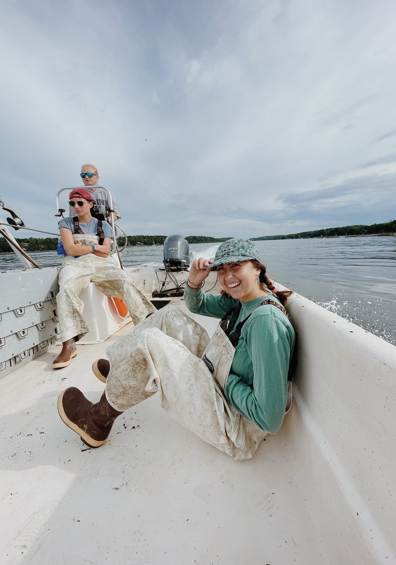 A young woman sits on a skiff, laughing.