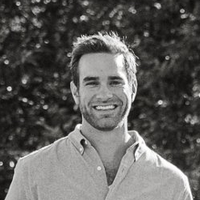 This is a black and white portrait of a man smiling.