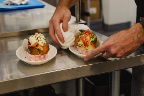 Someone is placing two seafood rolls on a counter.